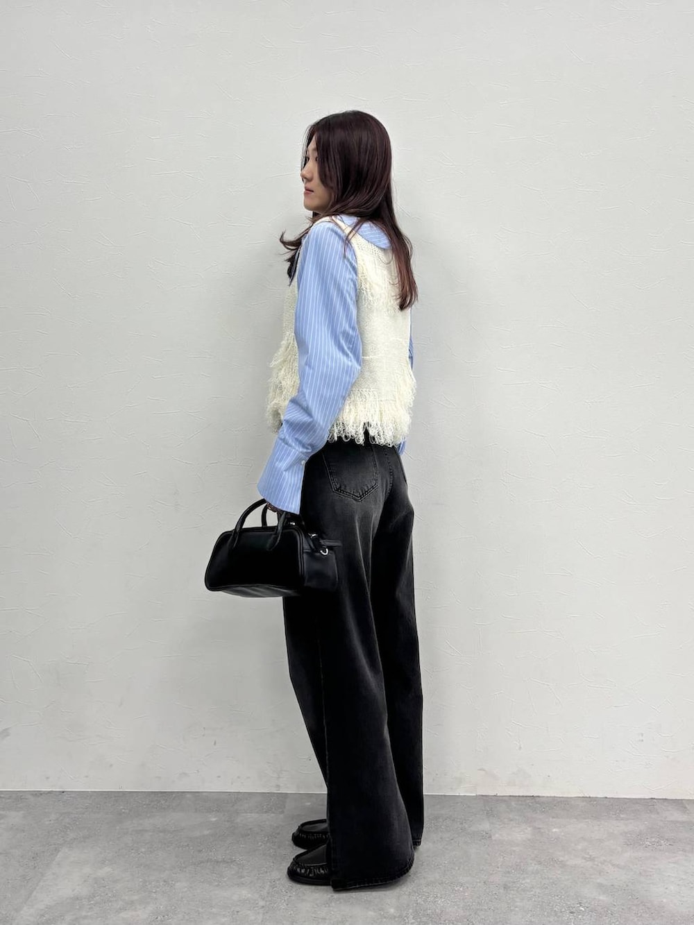 グレー系のデニムパンツ、ブラック系のボストンバッグ、ブラウン系のローファーを着用したレディースの冬コーディネートの4枚目の写真