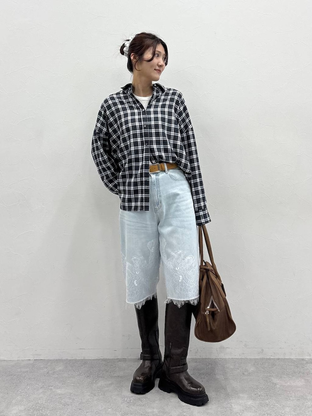 ブラウン系のボストンバッグ、ホワイト系のTシャツ/カットソー、ブラウン系のブーツを着用したレディースの夏コーディネートの3枚目の写真