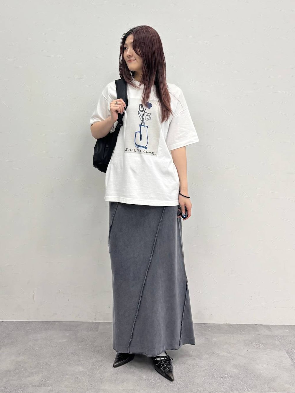 ブラック系のスカート、ホワイト系のTシャツ/カットソー、ブラック系のバックパック/リュックを着用したレディースの夏コーディネートの2枚目の写真