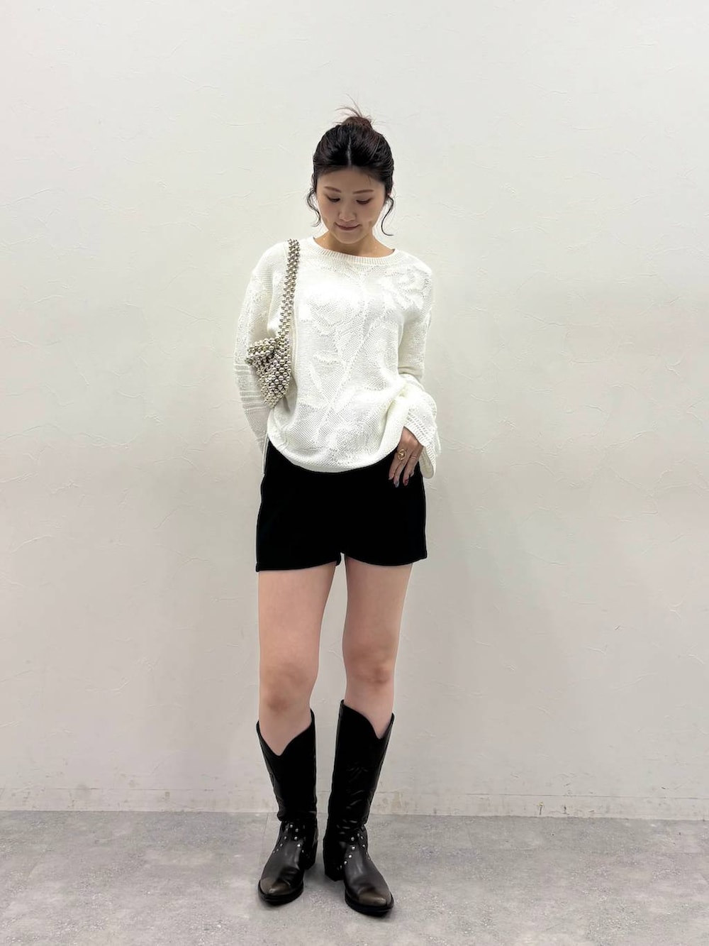 ブラック系のブーツ、ブラック系のスウェットパンツ、ホワイト系のニット/セーターを着用したレディースの冬コーディネートの2枚目の写真