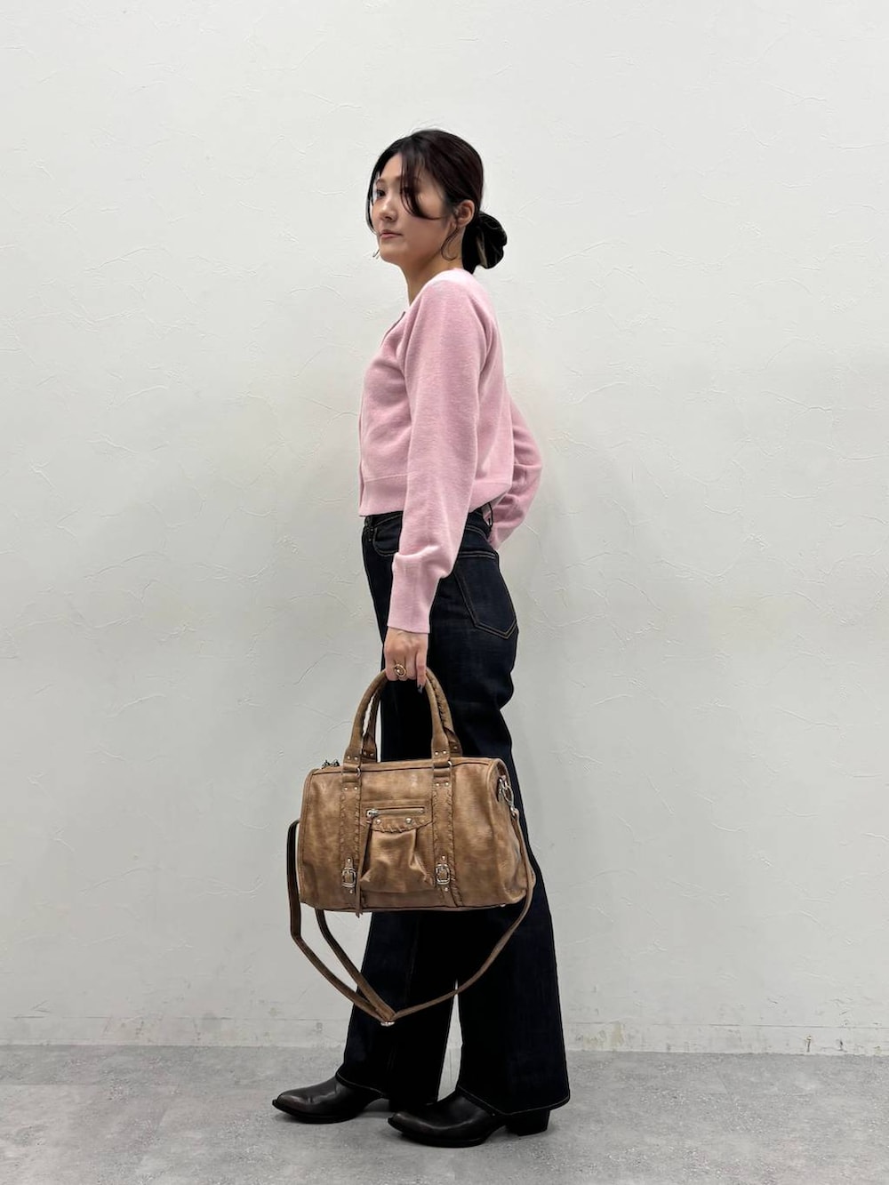 ブラック系のブーツ、ブラウン系のボストンバッグ、ブラック系のデニムパンツを着用したレディースの冬コーディネートの3枚目の写真