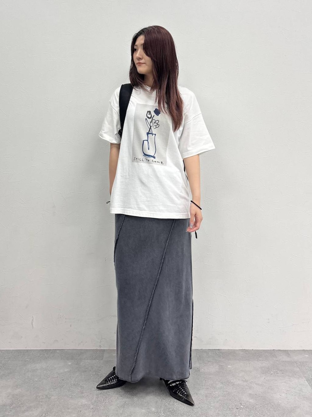 ブラック系のスカート、ホワイト系のTシャツ/カットソー、ブラック系のバックパック/リュックを着用したレディースの夏コーディネートの6枚目の写真