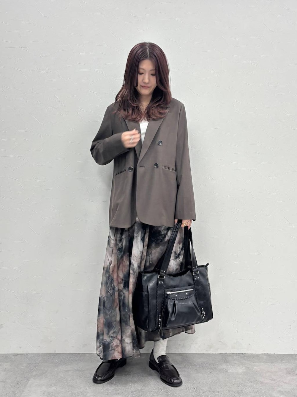 ブラック系のスカート、ブラウン系のテーラードジャケット、ブラック系のトートバッグを着用したレディースの冬コーディネートの2枚目の写真