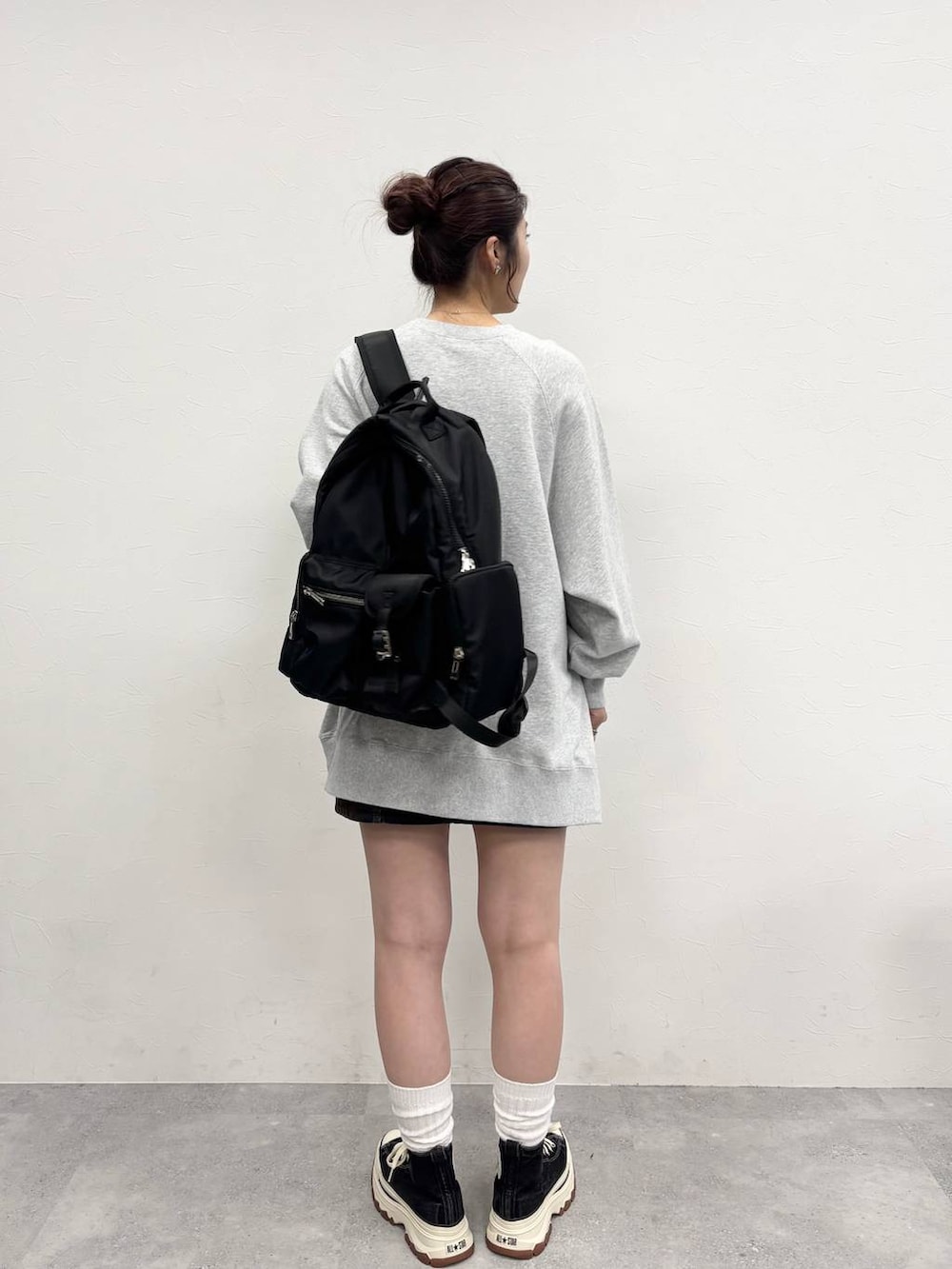 グレー系のスウェット、ブラック系のスニーカー、ブラウン系のデニムスカートを着用したレディースの冬コーディネートの4枚目の写真