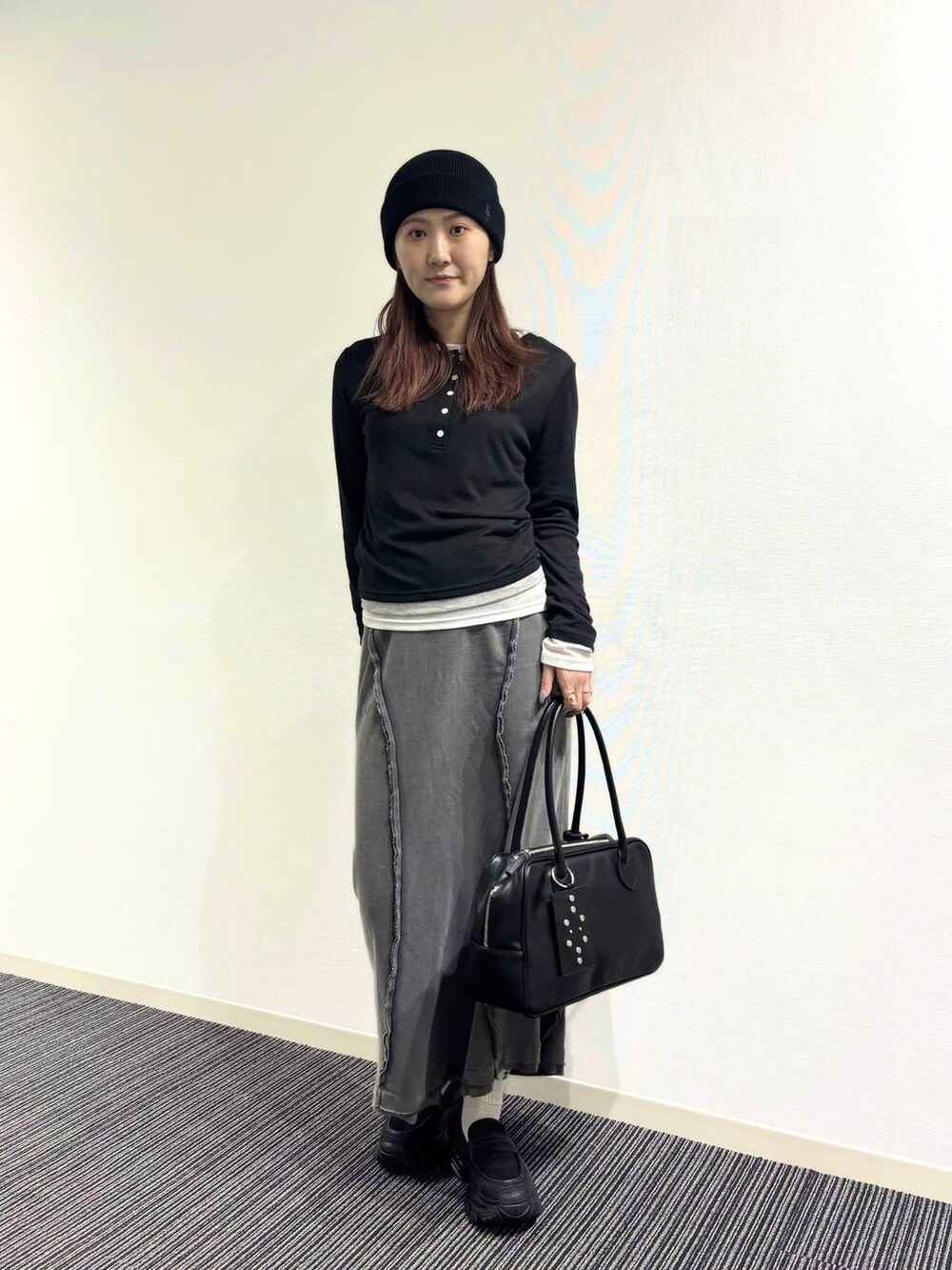 ブラック系のローファー、ブラック系のボストンバッグ、グレー系のスカートを着用したレディースの冬コーディネートの2枚目の写真