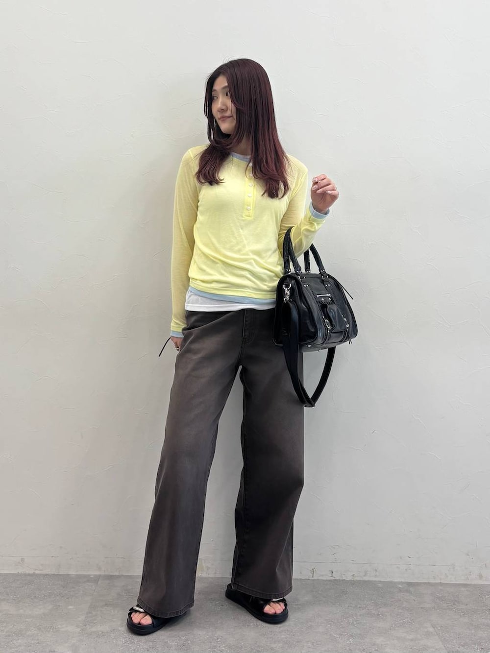 ブラック系のボストンバッグ、ブラック系のサンダル、ブラウン系のデニムパンツを着用したレディースの春コーディネートの2枚目の写真