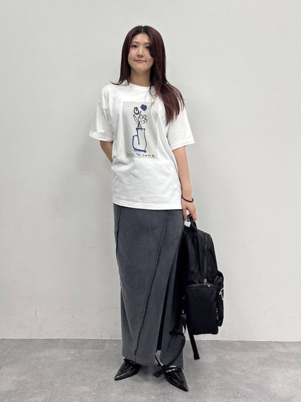 ブラック系のスカート、ホワイト系のTシャツ/カットソー、ブラック系のバックパック/リュックを着用したレディースの夏コーディネートの3枚目の写真