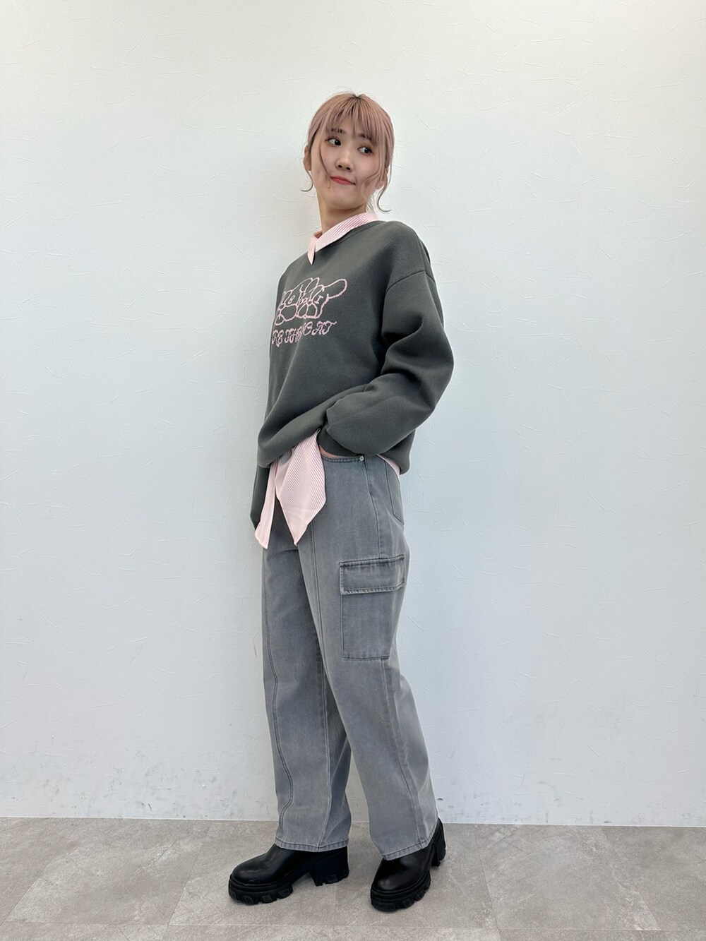 グレー系のニット/セーター、ピンク系のシャツ/ブラウス、ブラック系のデニムパンツを着用したレディースの春コーディネートの3枚目の写真