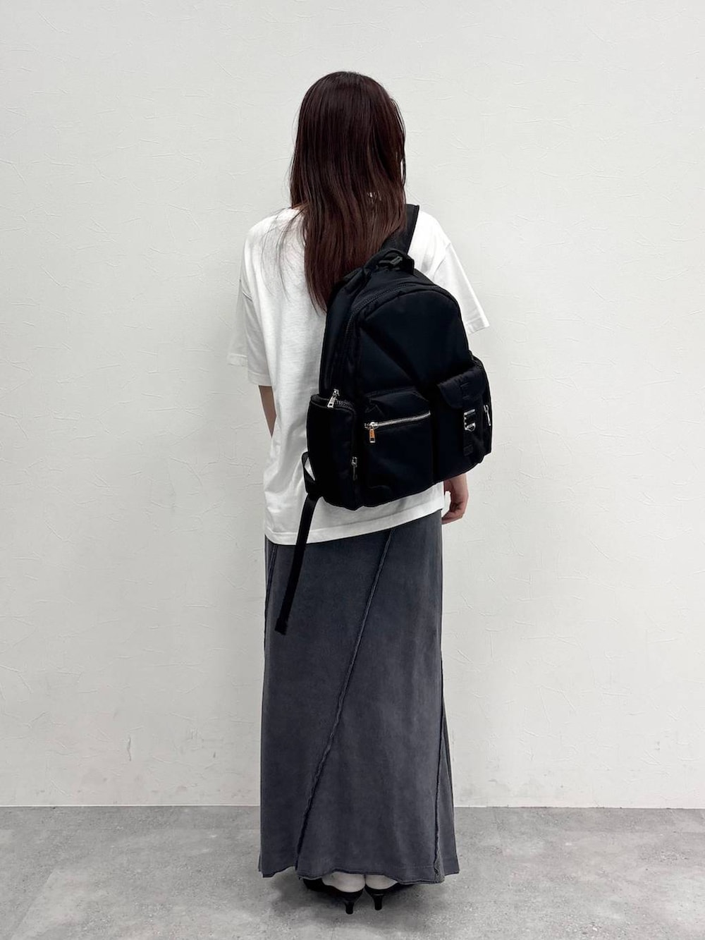 ブラック系のスカート、ホワイト系のTシャツ/カットソー、ブラック系のバックパック/リュックを着用したレディースの夏コーディネートの8枚目の写真
