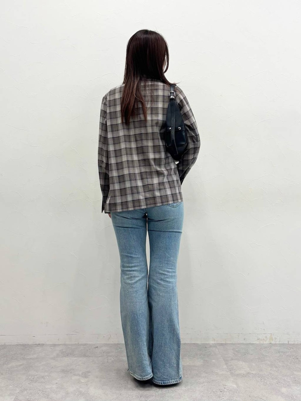 ブルー系のデニムパンツ、グレー系のテーラードジャケット、ブラック系のショルダーバッグを着用したレディースの春コーディネートの3枚目の写真