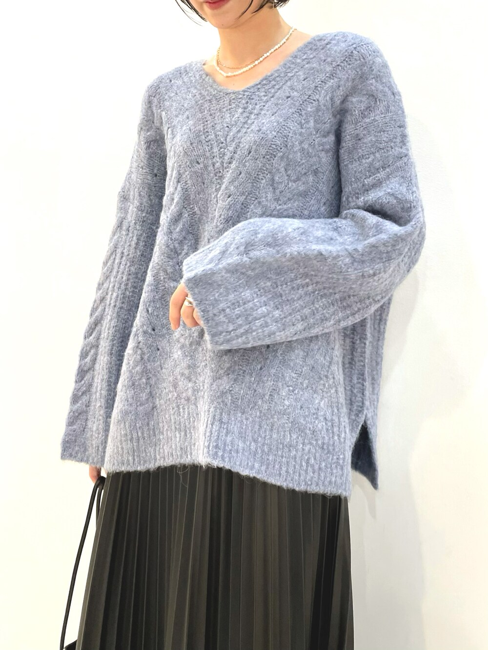 ブルー系のニット/セーター、ブラック系のスカート、ブラック系のショルダーバッグを着用したレディースの秋コーディネートの2枚目の写真