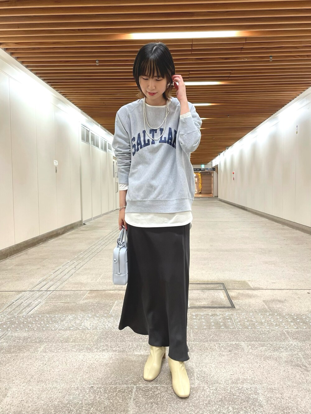 ベージュ系のトレンチコート、グレー系のスウェット、ホワイト系のTシャツ/カットソーを着用したレディースの冬コーディネートの2枚目の写真