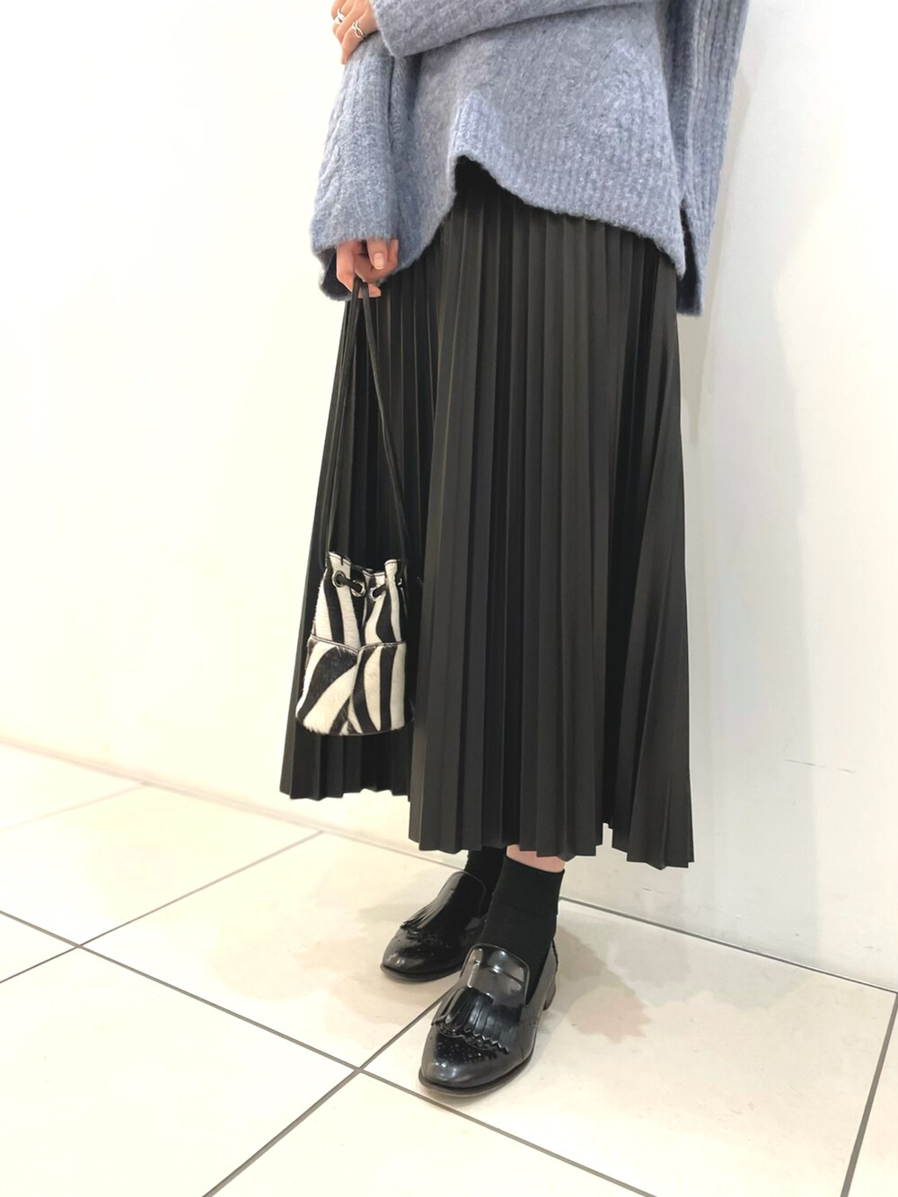 ブルー系のニット/セーター、ブラック系のスカート、ブラック系のショルダーバッグを着用したレディースの秋コーディネートの3枚目の写真