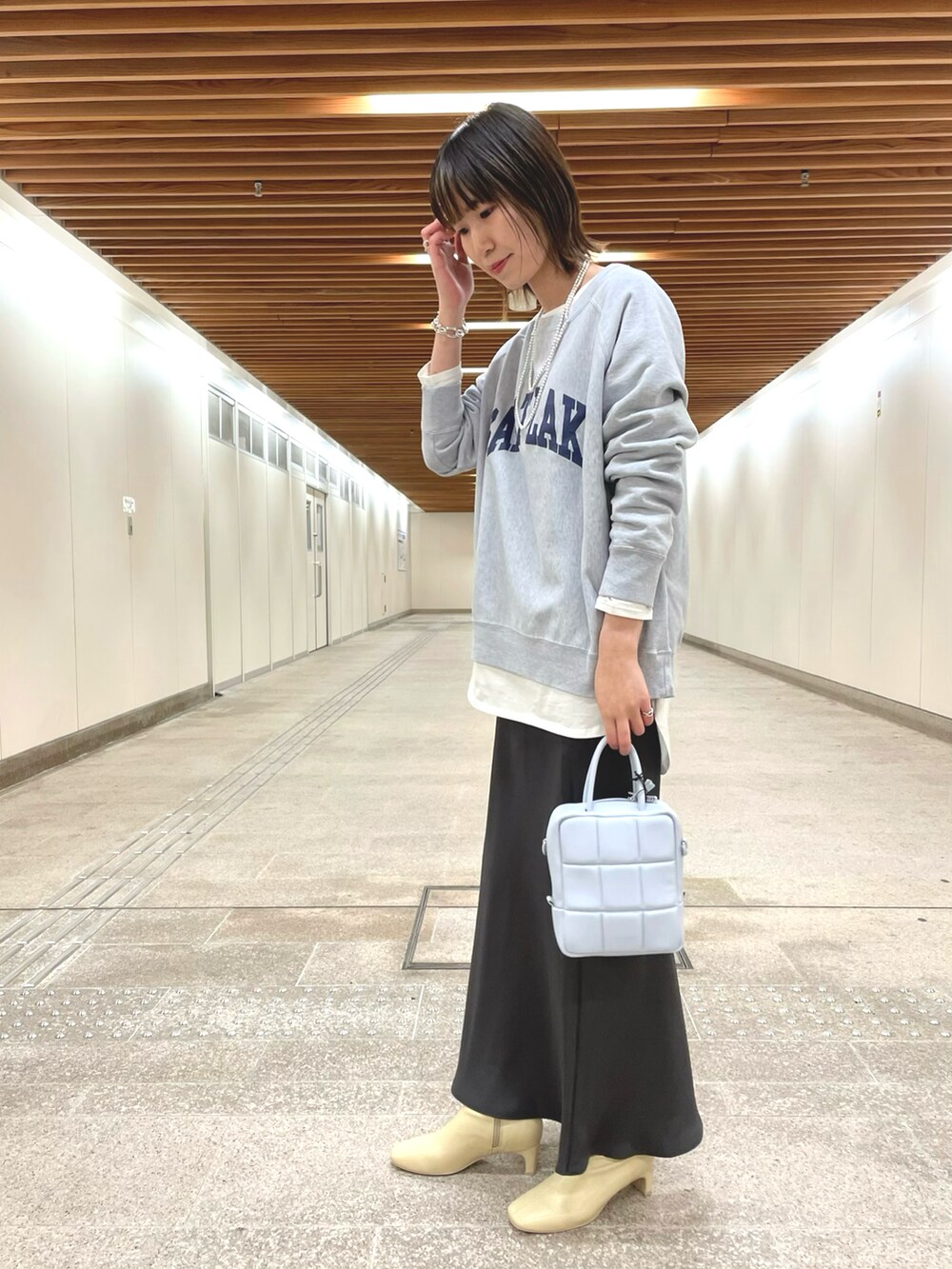 ベージュ系のトレンチコート、グレー系のスウェット、ホワイト系のTシャツ/カットソーを着用したレディースの冬コーディネートの3枚目の写真