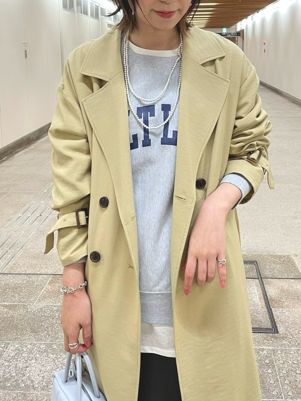 ベージュ系のトレンチコート、グレー系のスウェット、ホワイト系のTシャツ/カットソーを着用したレディースの冬コーディネートの4枚目の写真