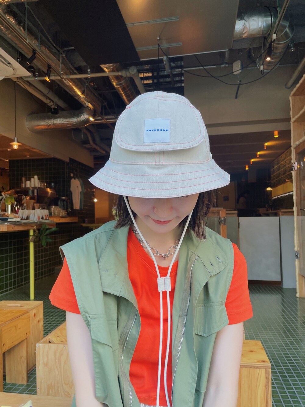 グリーン系のベスト、ホワイト系のカーゴパンツ、ブラック系のサンダルを着用したレディースの夏コーディネートの3枚目の写真