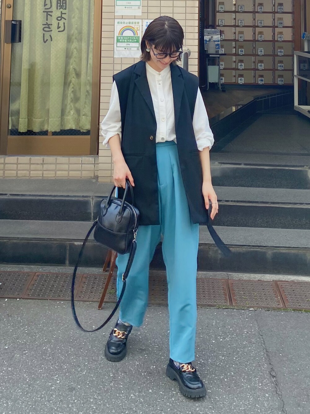 ブラック系のショルダーバッグ、ブルー系のスラックス、ブラック系のローファーを着用したレディースの春コーディネートの3枚目の写真