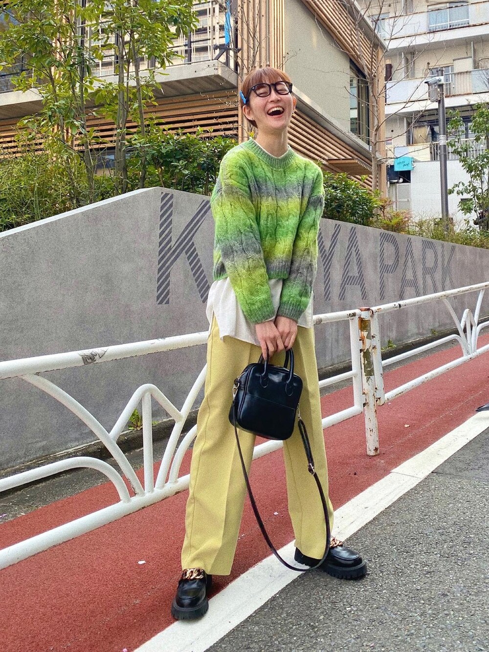 ブラック系のショルダーバッグ、ブラック系のローファー、イエロー系のスラックスを着用したレディースの春コーディネートの2枚目の写真