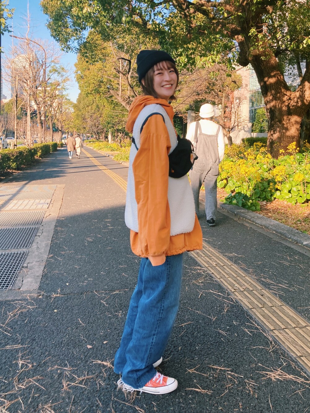 オレンジ系のジャケット/アウター、ブルー系のデニムパンツ、オレンジ系のスニーカーを着用したレディースの冬コーディネートの2枚目の写真