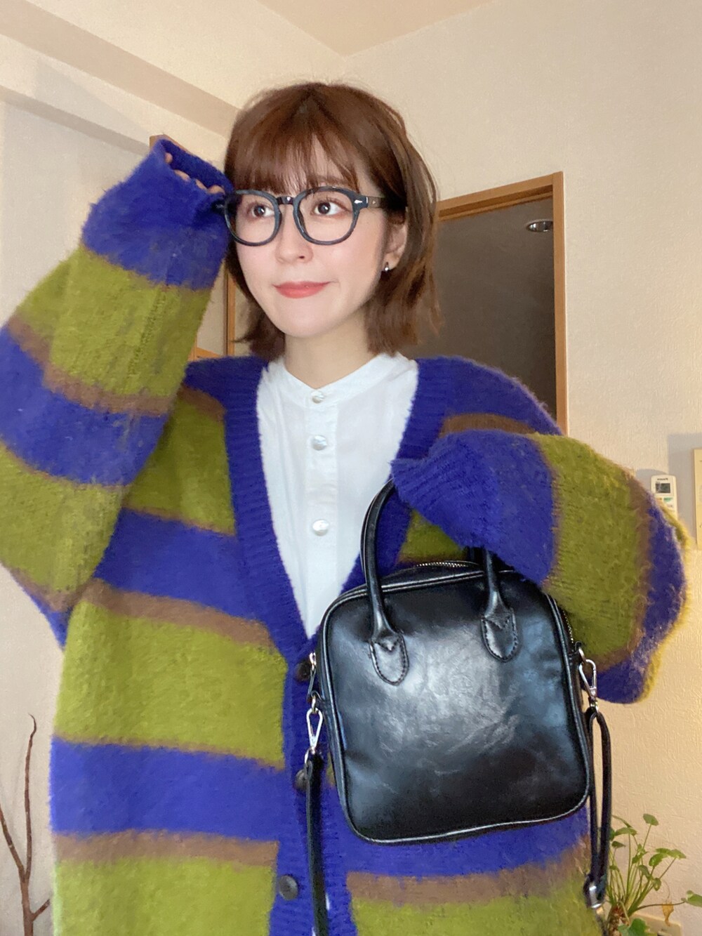 イエロー系のスラックス、ホワイト系のスニーカー、ブルー系のカーディガン/ボレロを着用したレディースの冬コーディネートの2枚目の写真