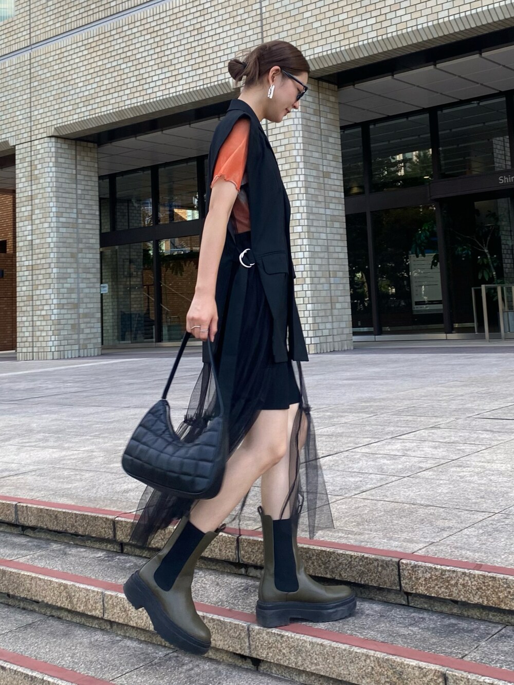 オレンジ系のTシャツ/カットソー、ブラック系のパンツ、グリーン系のブーツを着用したレディースの秋コーディネートの3枚目の写真