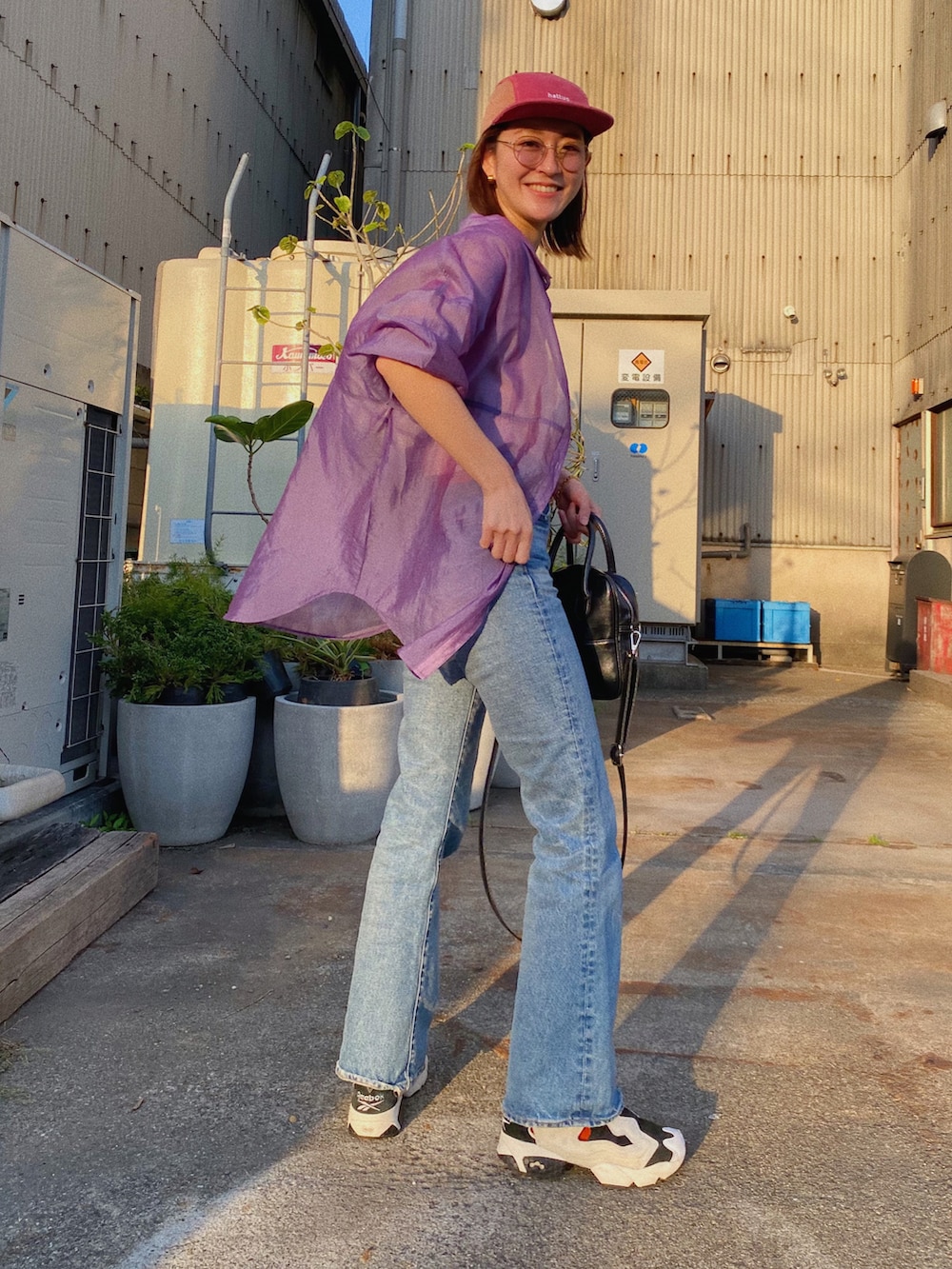 ブラック系のショルダーバッグ、ブルー系のデニムパンツ、ホワイト系のスニーカーを着用したレディースの春コーディネートの2枚目の写真