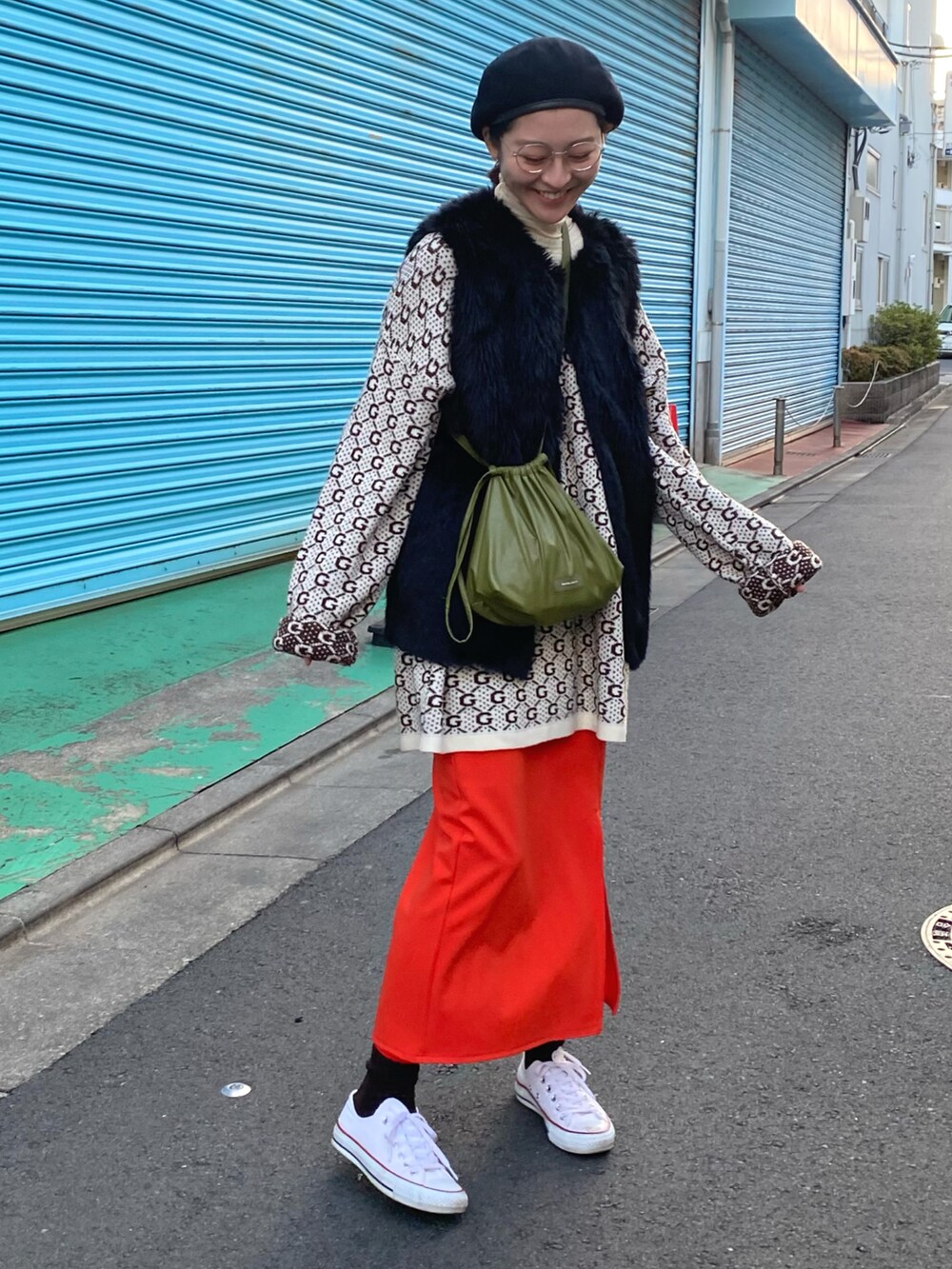 オレンジ系のスカート、ホワイト系のスニーカー、グリーン系のショルダーバッグを着用したレディースの冬コーディネートの2枚目の写真