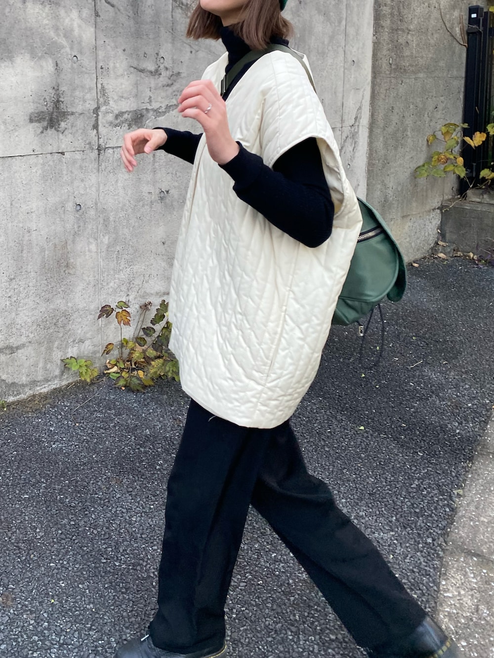 ホワイト系のノーカラーコート、ブラック系のブーツ、グリーン系のショルダーバッグを着用したレディースの秋コーディネートの3枚目の写真