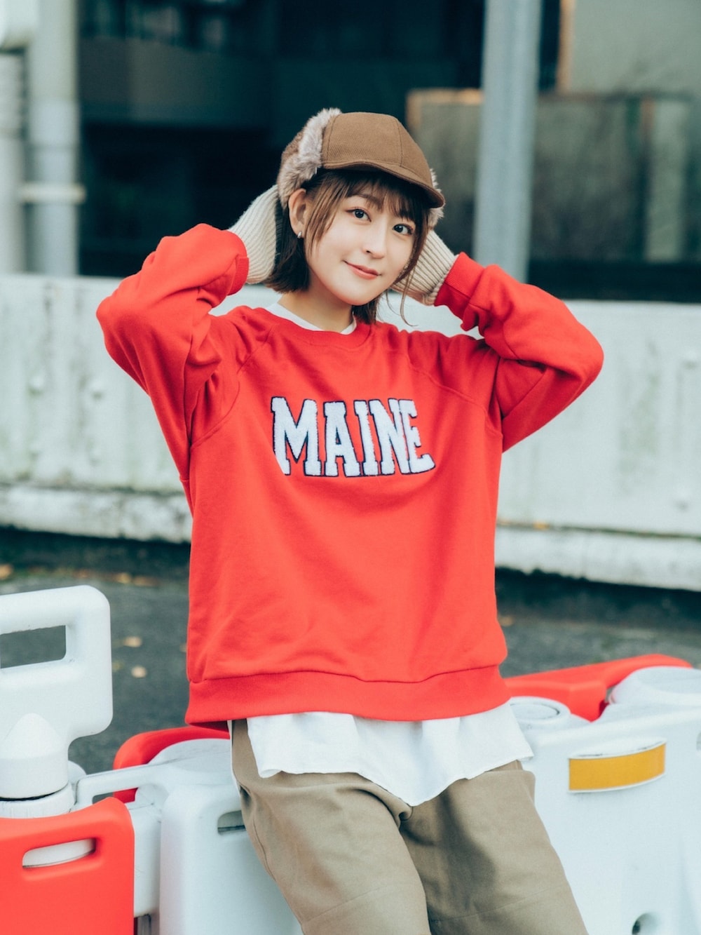 レッド系のトップス、ベージュ系のパンツ、グリーン系のブーツを着用したレディースの冬コーディネートの2枚目の写真