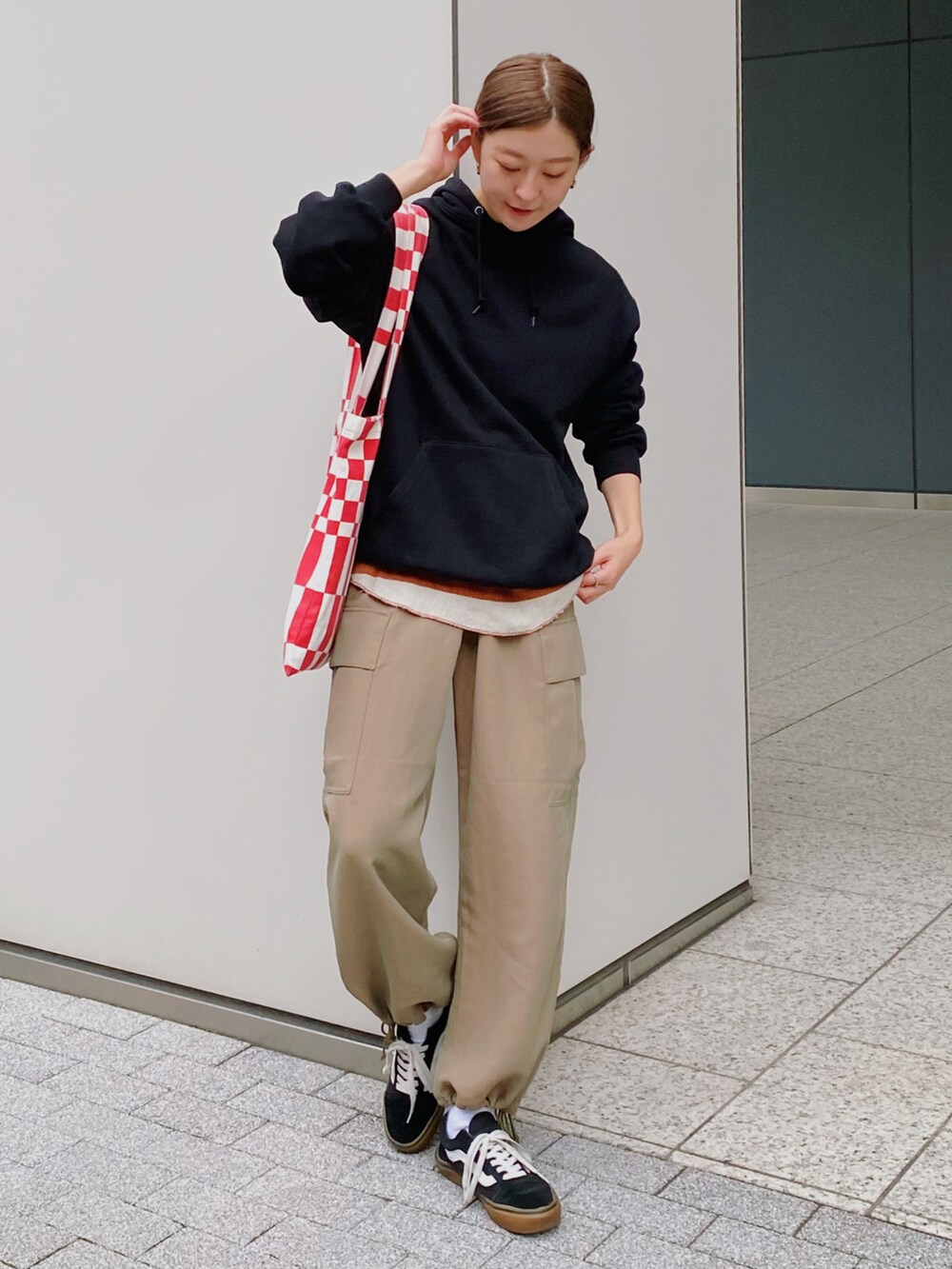 ブラック系のパーカー、グリーン系のカーゴパンツ、ブラック系のスニーカーを着用したレディースの秋コーディネートの3枚目の写真