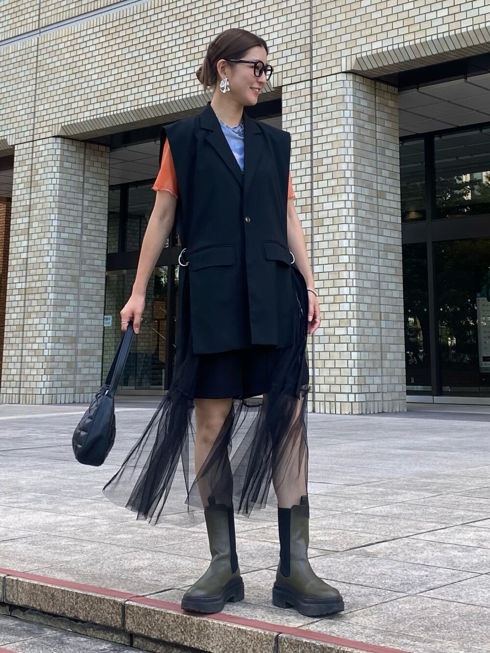 オレンジ系のTシャツ/カットソー、ブラック系のパンツ、グリーン系のブーツを着用したレディースの秋コーディネートの2枚目の写真