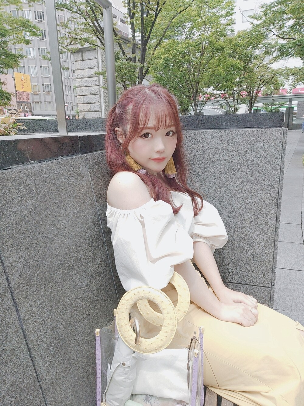 パープル系のハンドバッグ、イエロー系のスカート、ホワイト系のTシャツ/カットソーを着用したレディースの夏コーディネートの2枚目の写真