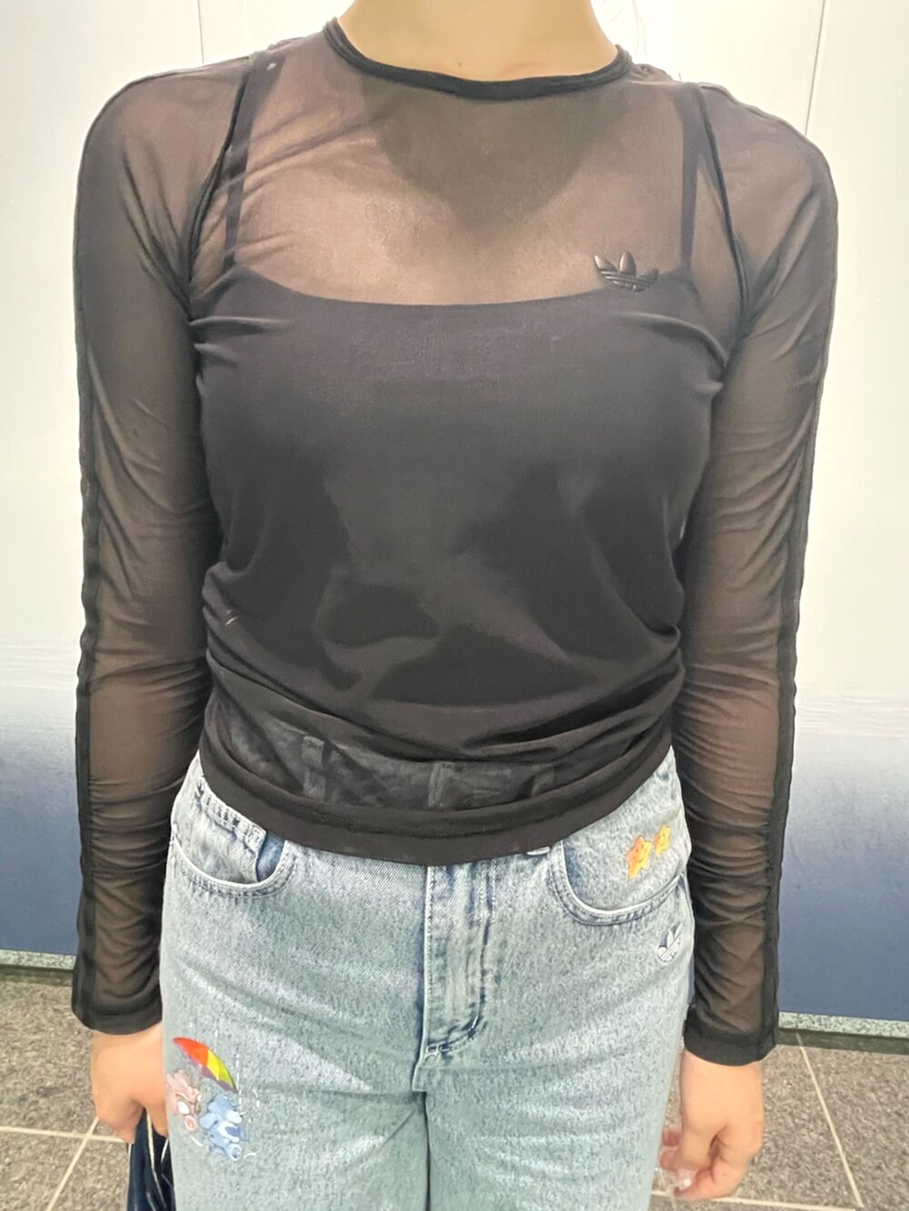 ブラック系のトップス、ブルー系のショルダーバッグ、ブルー系のデニムパンツを着用したレディースの夏コーディネートの2枚目の写真