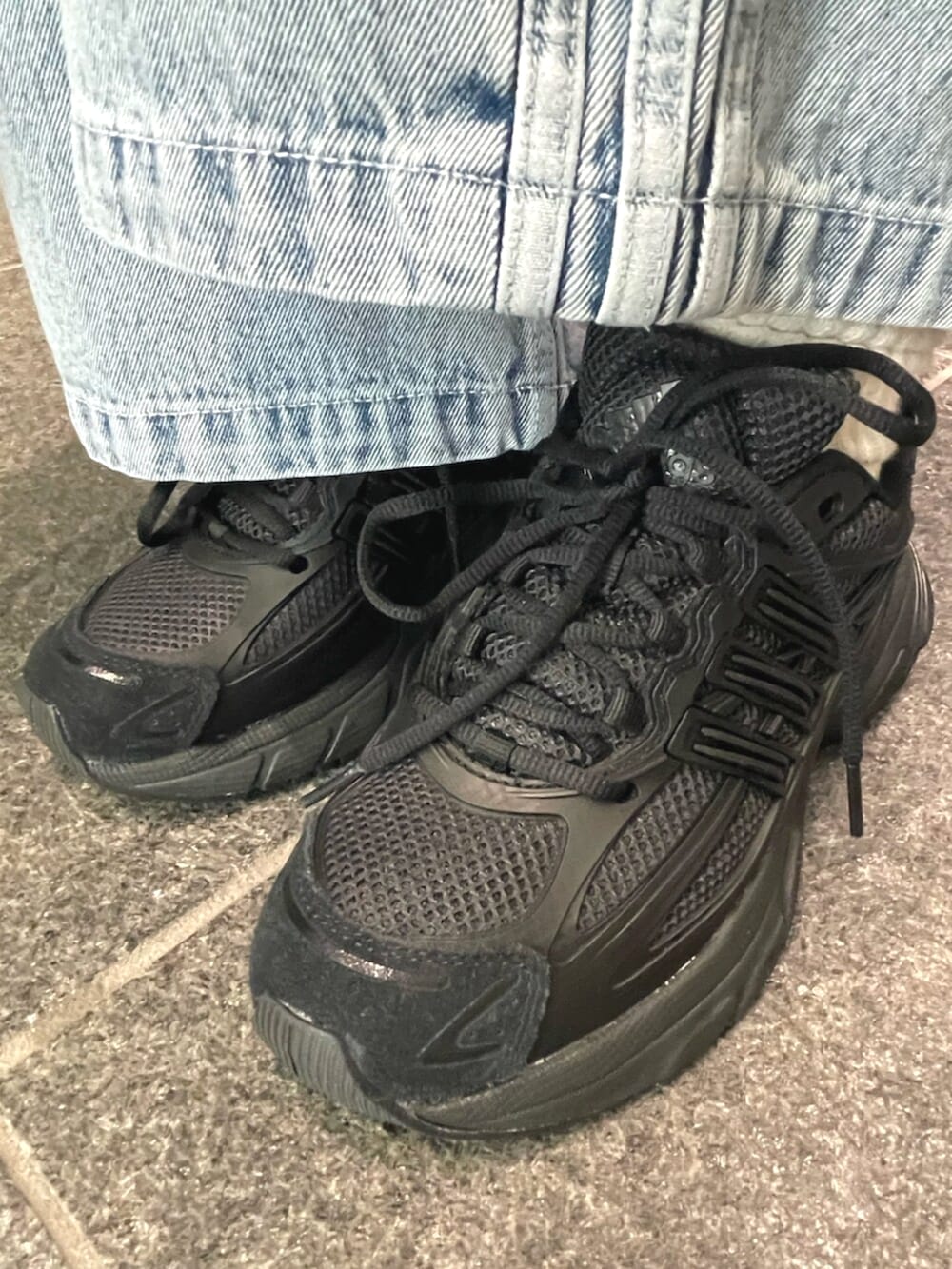 ブラック系のトップス、ブルー系のショルダーバッグ、ブルー系のデニムパンツを着用したレディースの夏コーディネートの4枚目の写真