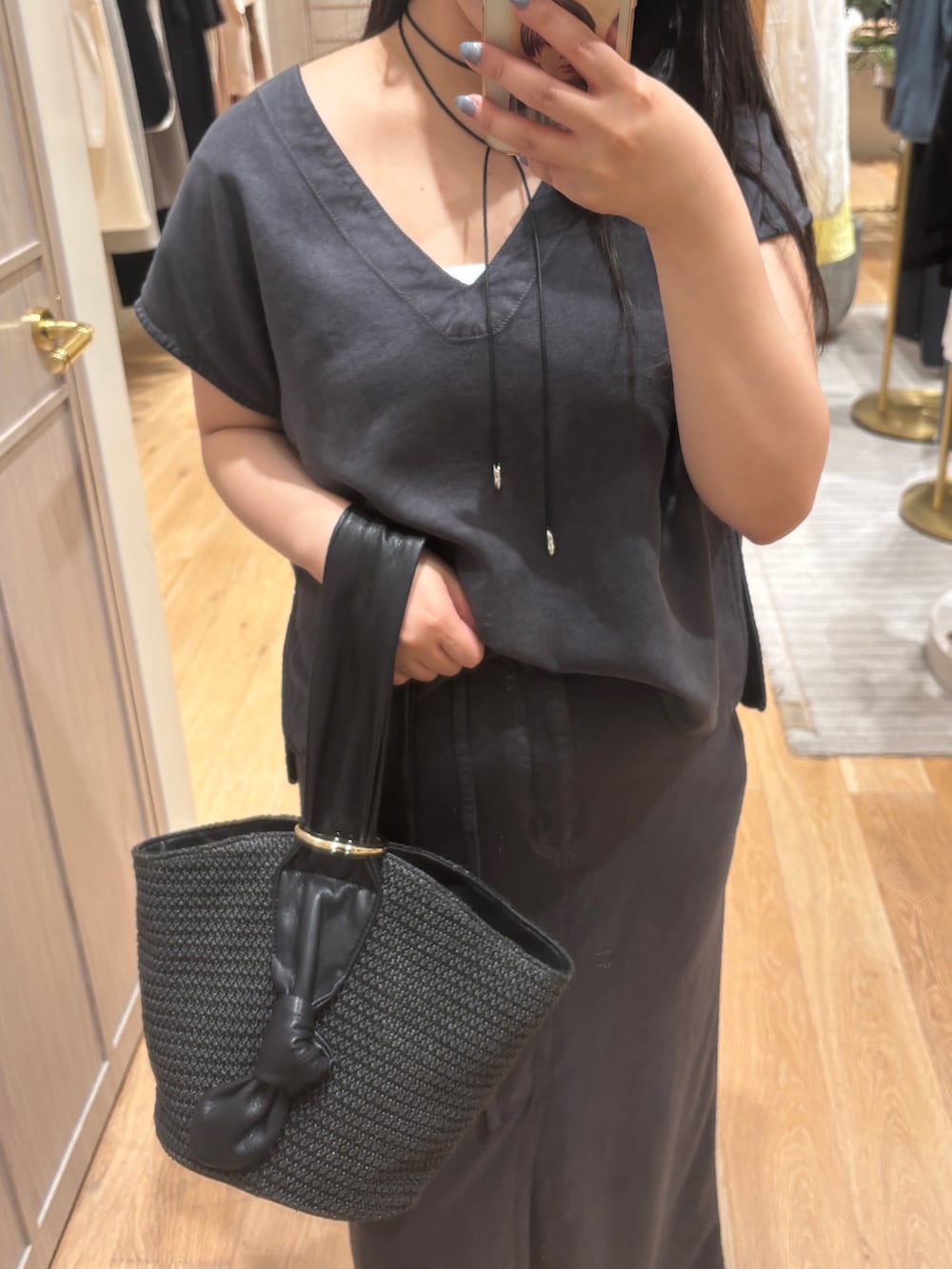 グレー系のシャツ/ブラウス、グレー系のスカート、ブラック系のかごバッグを着用したレディースの夏コーディネートの2枚目の写真