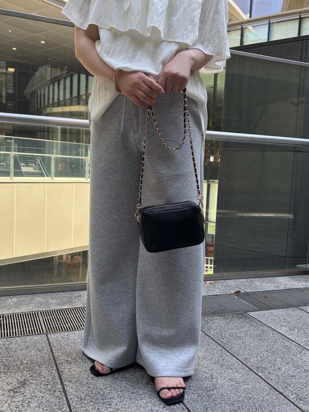 ホワイト系のシャツ/ブラウス、グレー系のスウェットパンツ、ブラック系のショルダーバッグを着用したレディースの夏コーディネートの4枚目の写真