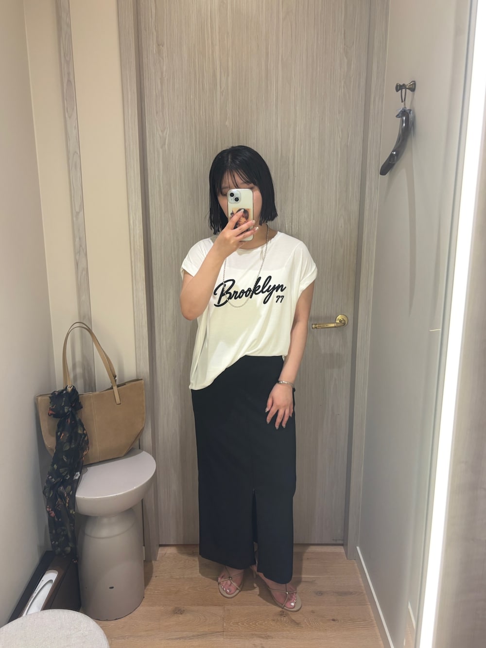 ホワイト系のTシャツ/カットソー、ブラック系のスカート、ベージュ系のサンダルを着用したレディースの夏コーディネートの4枚目の写真