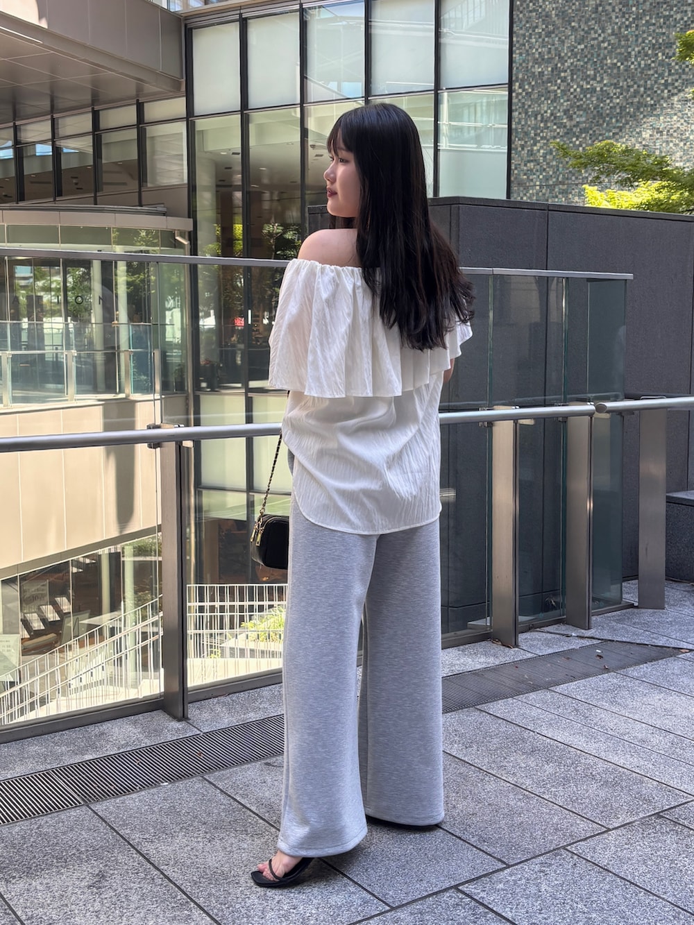 ホワイト系のシャツ/ブラウス、グレー系のスウェットパンツ、ブラック系のショルダーバッグを着用したレディースの夏コーディネートの2枚目の写真