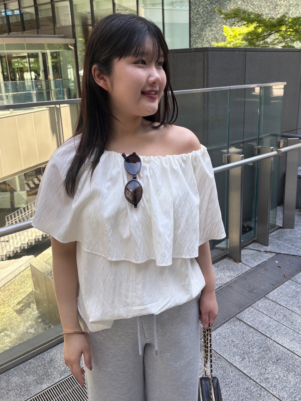 ホワイト系のシャツ/ブラウス、グレー系のスウェットパンツ、ブラック系のショルダーバッグを着用したレディースの夏コーディネートの3枚目の写真
