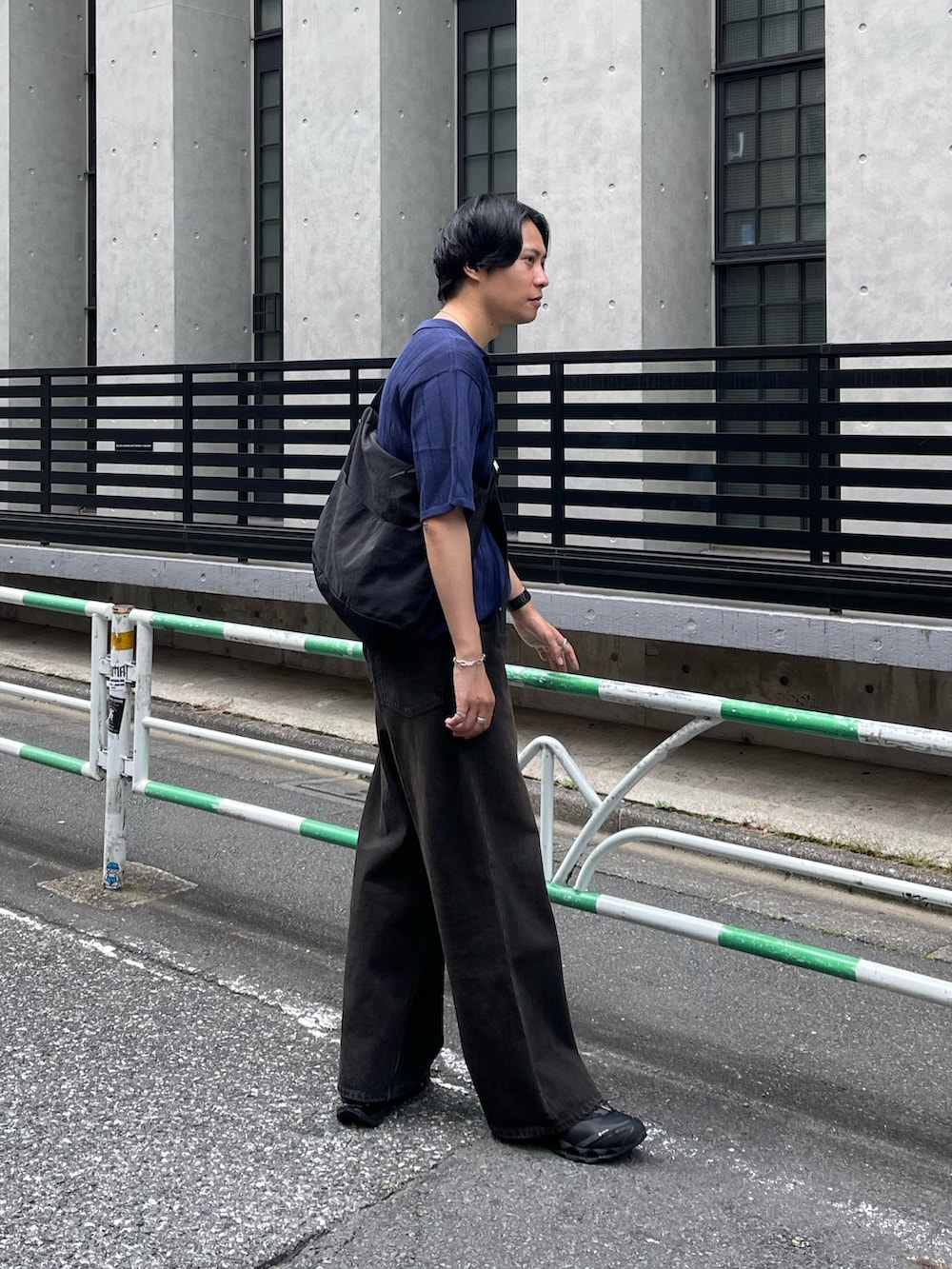 ブラック系のデニムパンツ、ブルー系のニット/セーター、ブラック系のショルダーバッグを着用したメンズの夏コーディネートの3枚目の写真