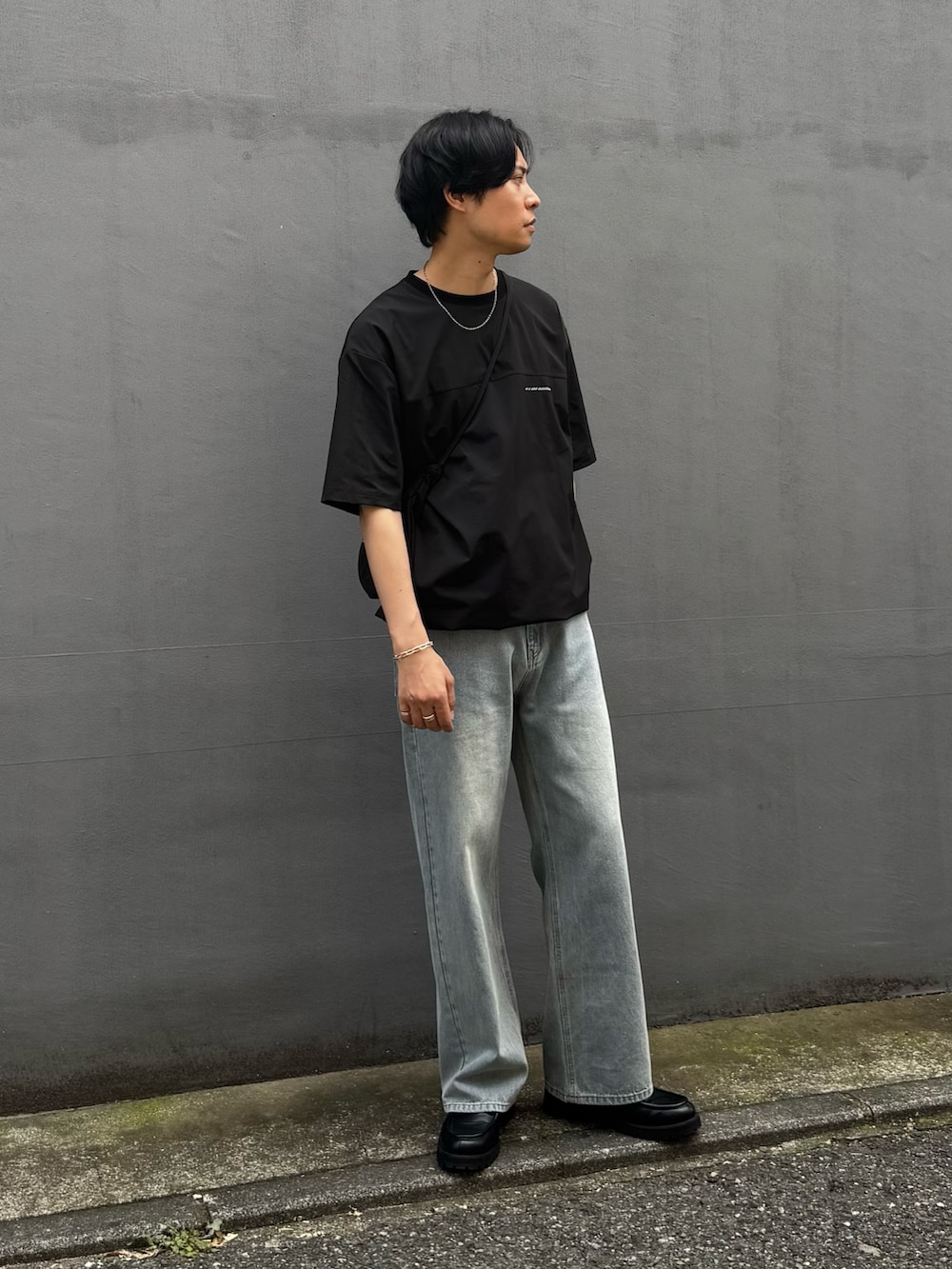 ブラック系のTシャツ/カットソー、ブラック系のショルダーバッグ、ブルー系のデニムパンツを着用したメンズの夏コーディネートの2枚目の写真