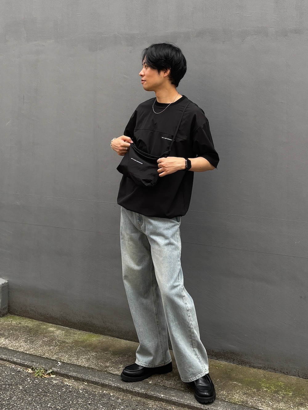 ブラック系のTシャツ/カットソー、ブラック系のショルダーバッグ、ブルー系のデニムパンツを着用したメンズの夏コーディネートの4枚目の写真