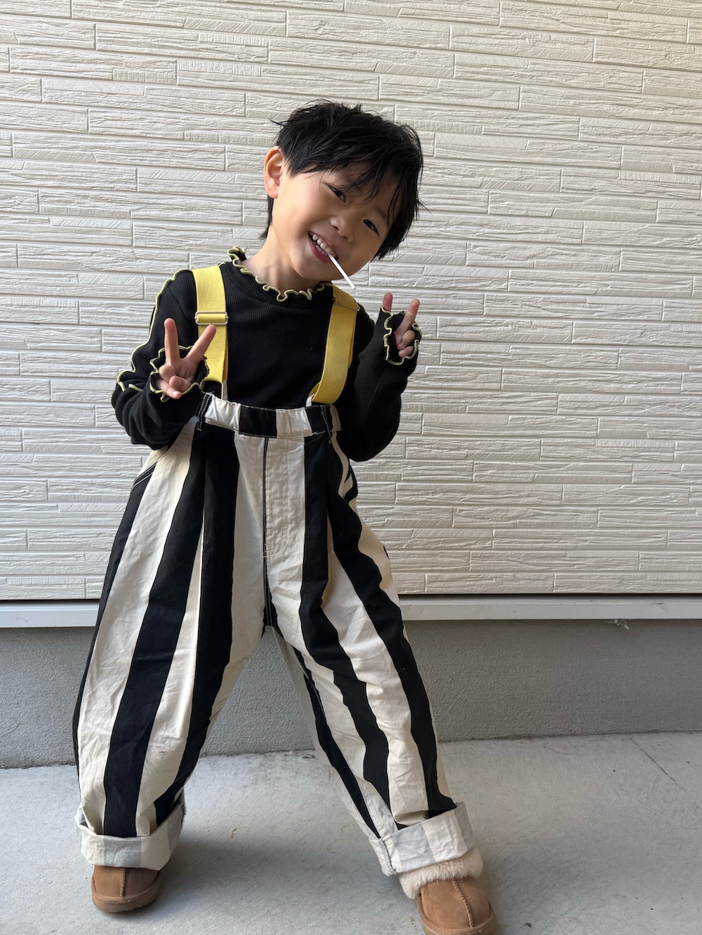 ブラック系のTシャツ/カットソー、ブラック系のサロペット/オーバーオール、ブラウン系のスリッポンを着用したキッズの冬コーディネートの2枚目の写真