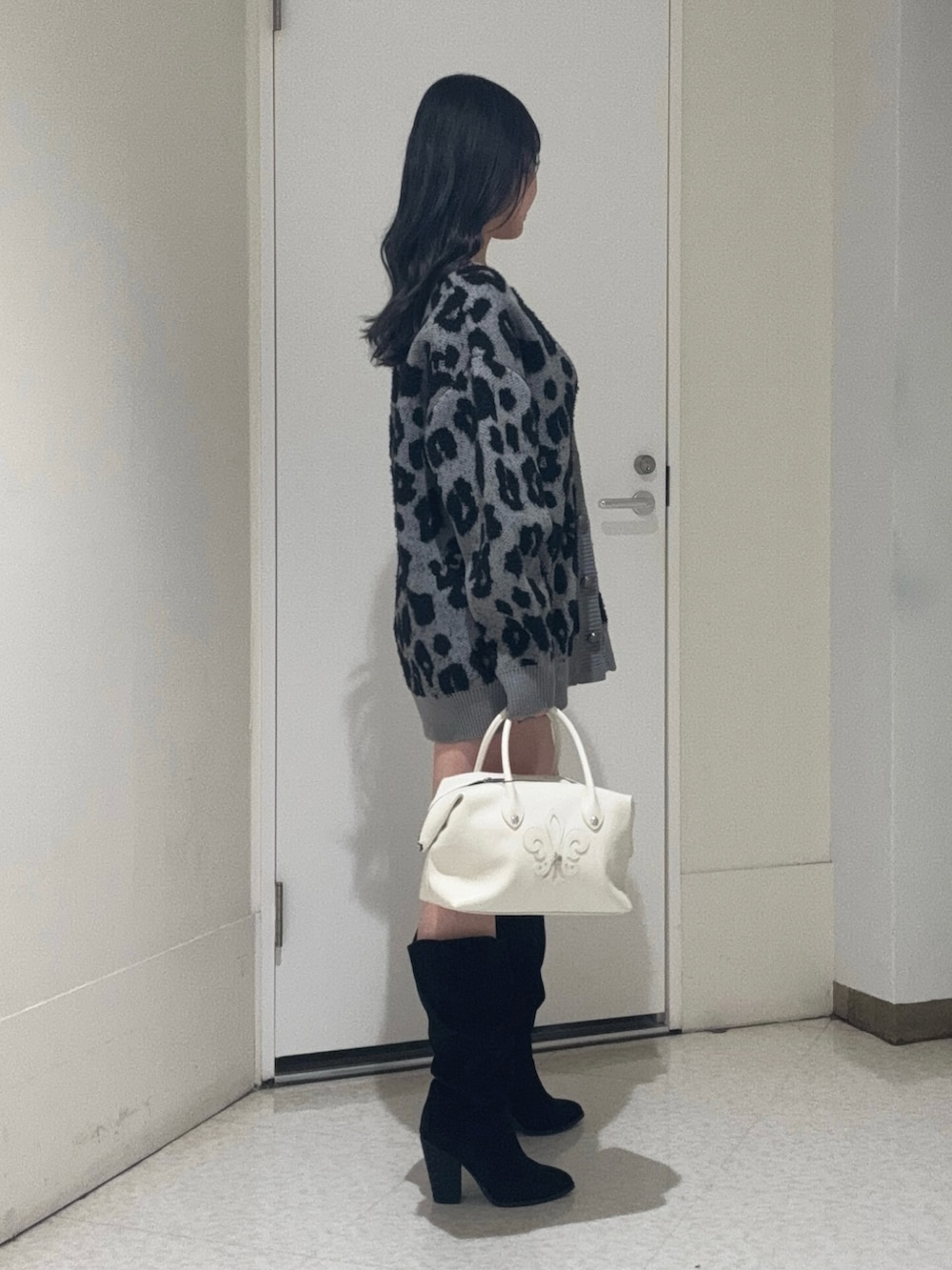 グレー系のカーディガン/ボレロ、ホワイト系のボストンバッグ、ブラック系のブーツを着用したレディースの冬コーディネートの2枚目の写真
