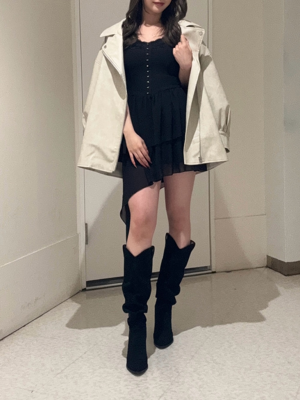 ブラック系のワンピース、ホワイト系のライダースジャケット、ブラック系のブーツを着用したレディースの春コーディネートの3枚目の写真