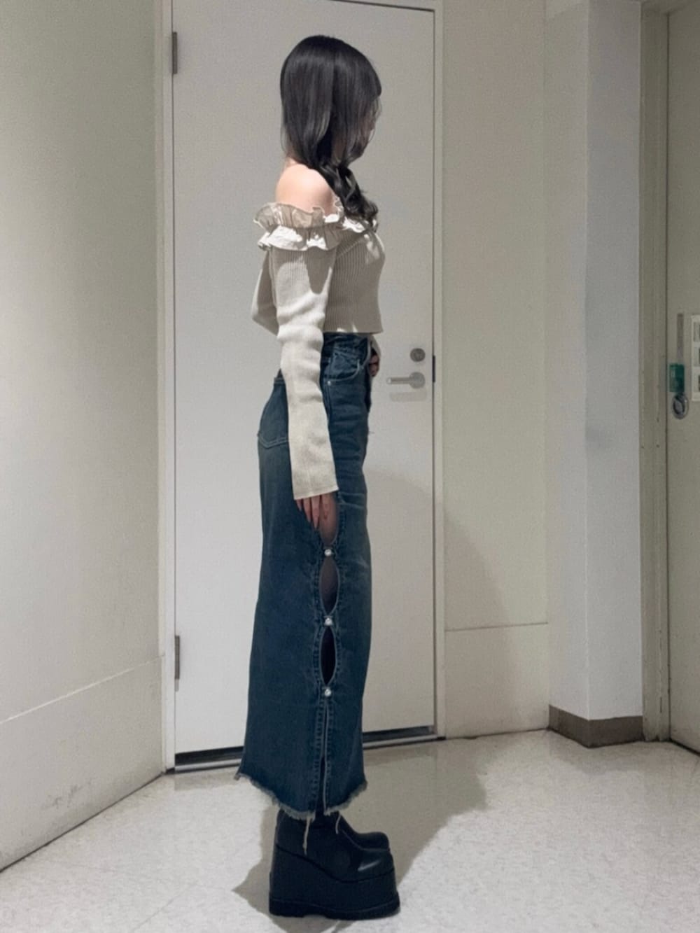 ブラック系のブーツ、ベージュ系のニット/セーター、ブルー系のデニムスカートを着用したレディースの春コーディネートの2枚目の写真