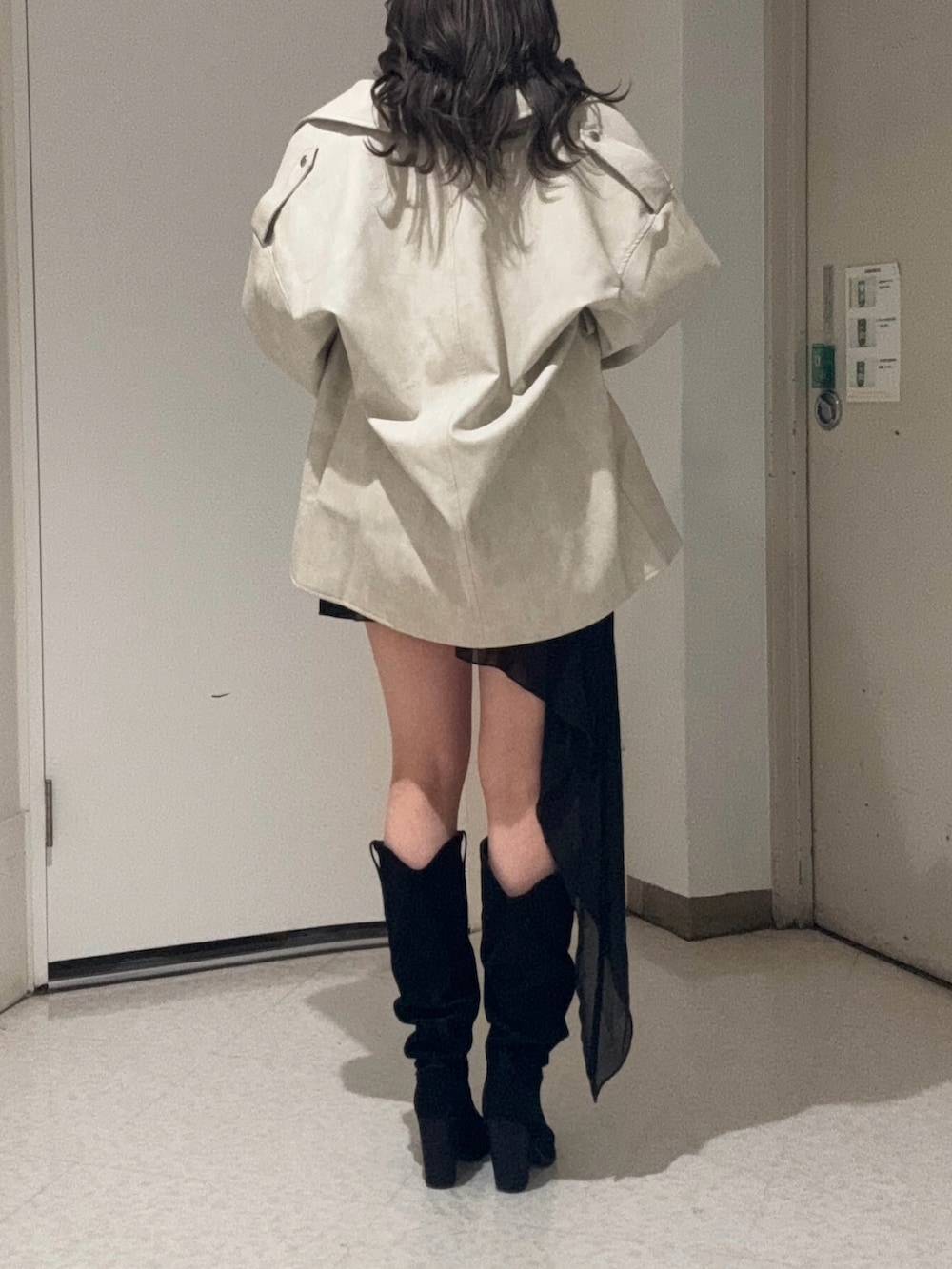 ブラック系のワンピース、ホワイト系のライダースジャケット、ブラック系のブーツを着用したレディースの春コーディネートの5枚目の写真