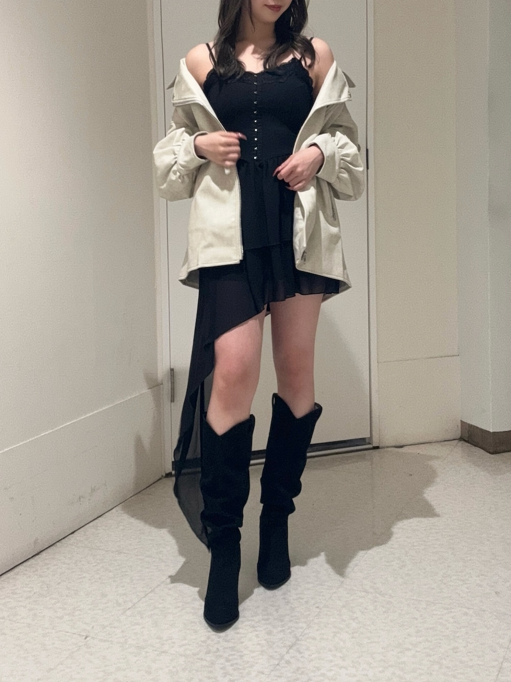 ブラック系のワンピース、ホワイト系のライダースジャケット、ブラック系のブーツを着用したレディースの春コーディネートの2枚目の写真