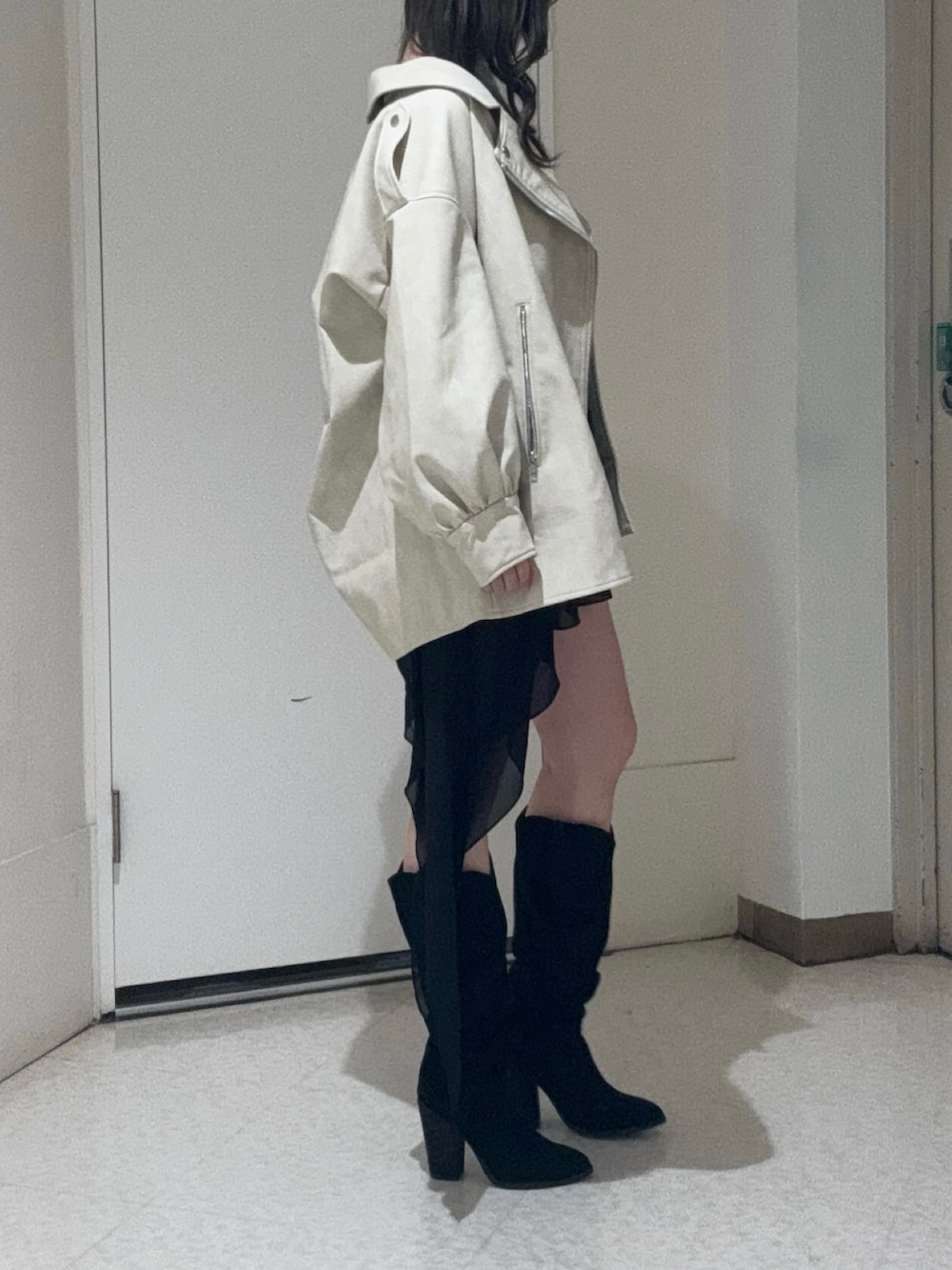 ブラック系のワンピース、ホワイト系のライダースジャケット、ブラック系のブーツを着用したレディースの春コーディネートの4枚目の写真