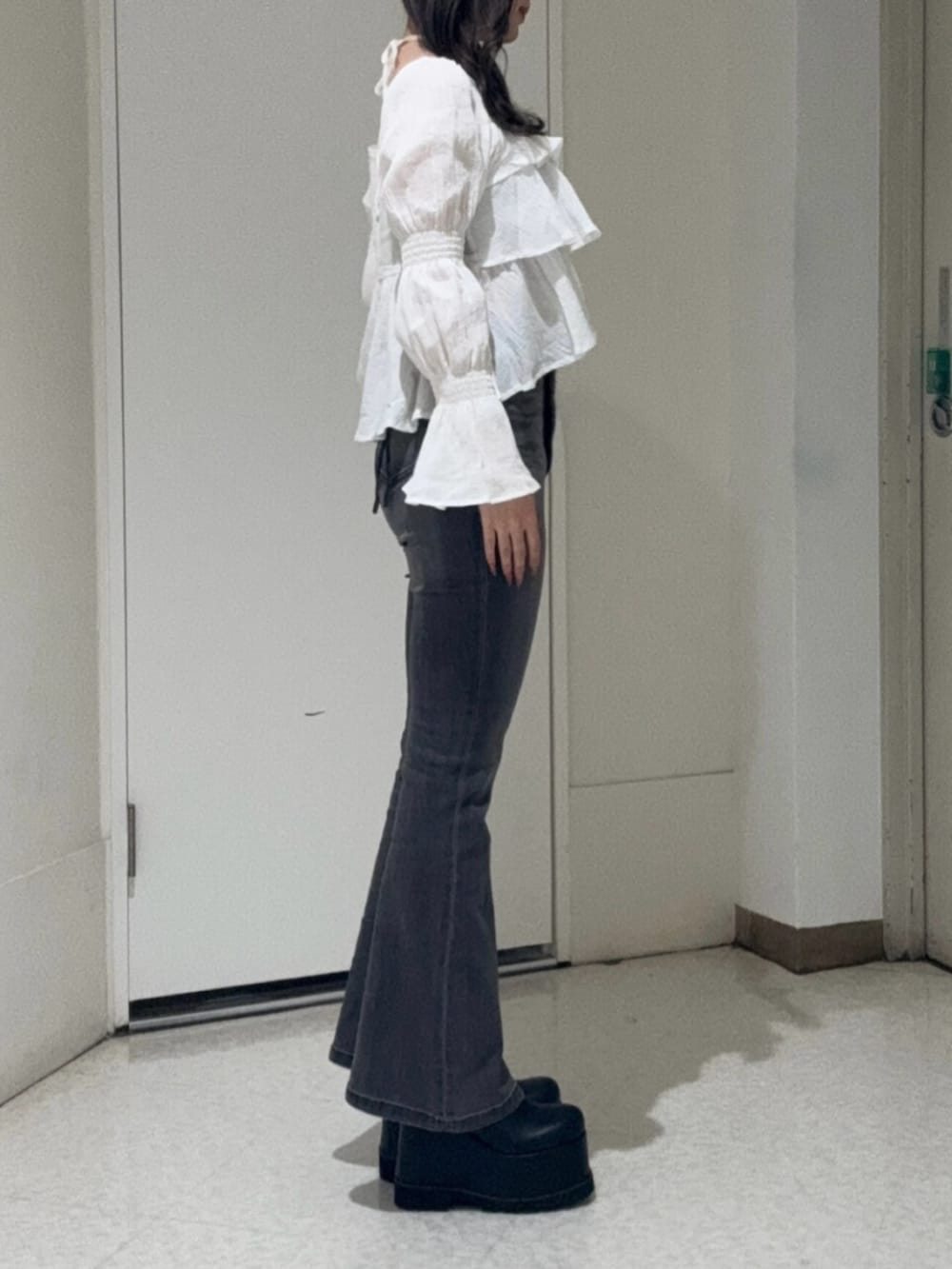 ブラック系のブーツ、ブラック系のデニムパンツ、ブラック系のショルダーバッグを着用したレディースの春コーディネートの2枚目の写真